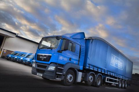 Blue Menzies lorry parked in the foreground, with a row of blue vans parked in the background.