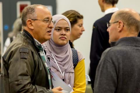 Two men and one woman in hijab in discussion at OR59