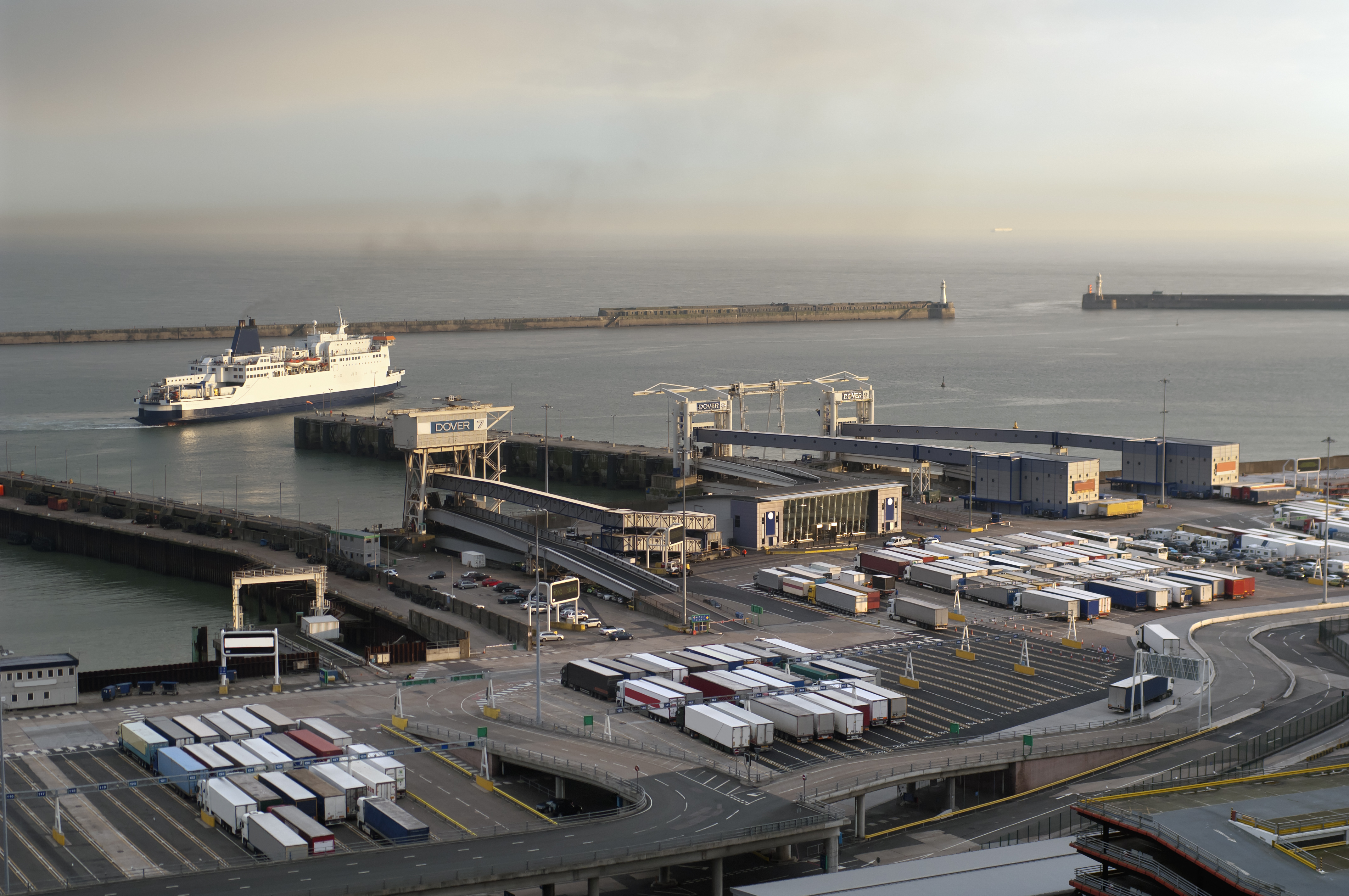 Shipping port with containers on shore and a ship going out to sea in the distance.
