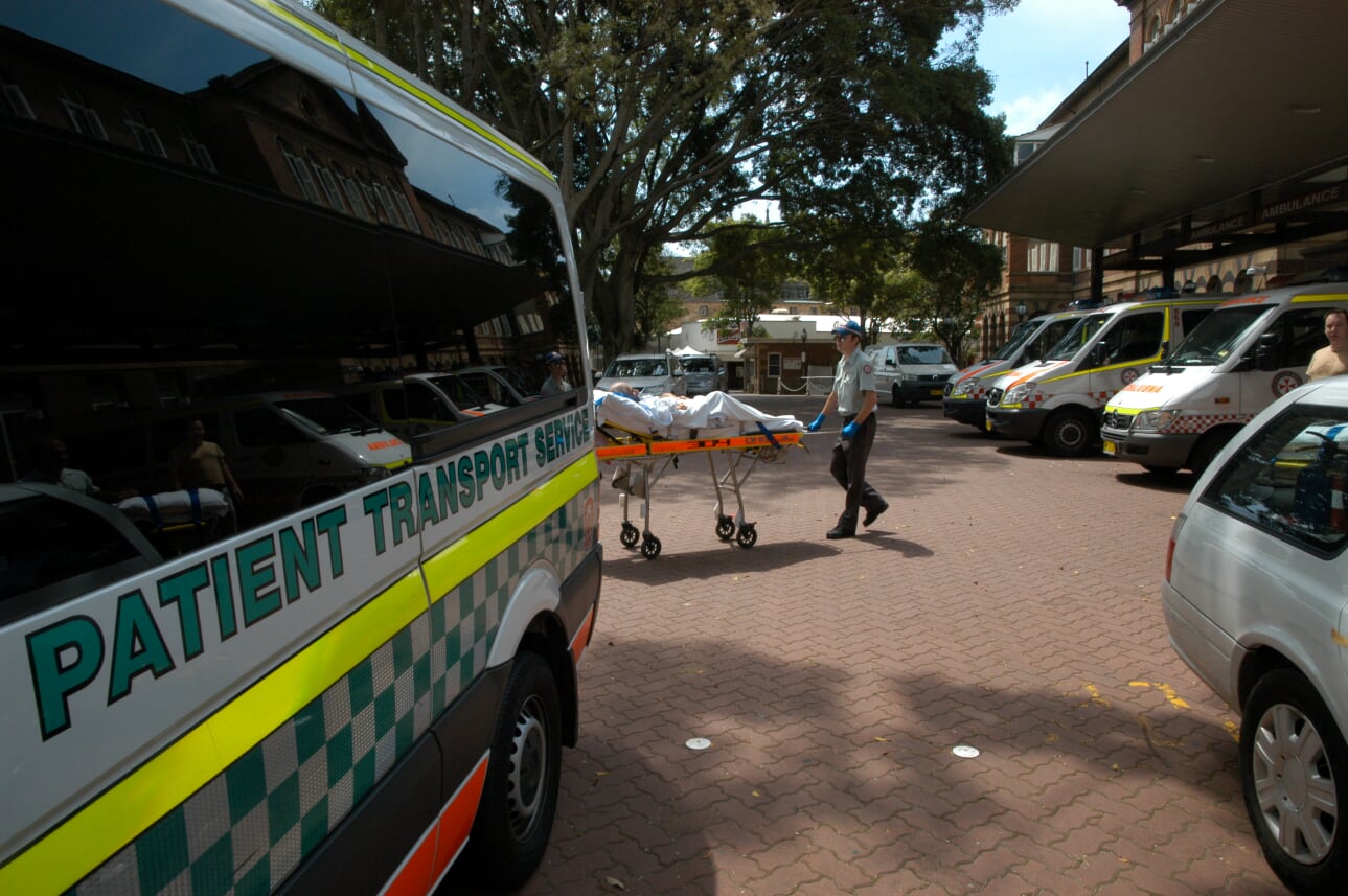 Patient on stretcher being wheeled towards Patient Transport van.
