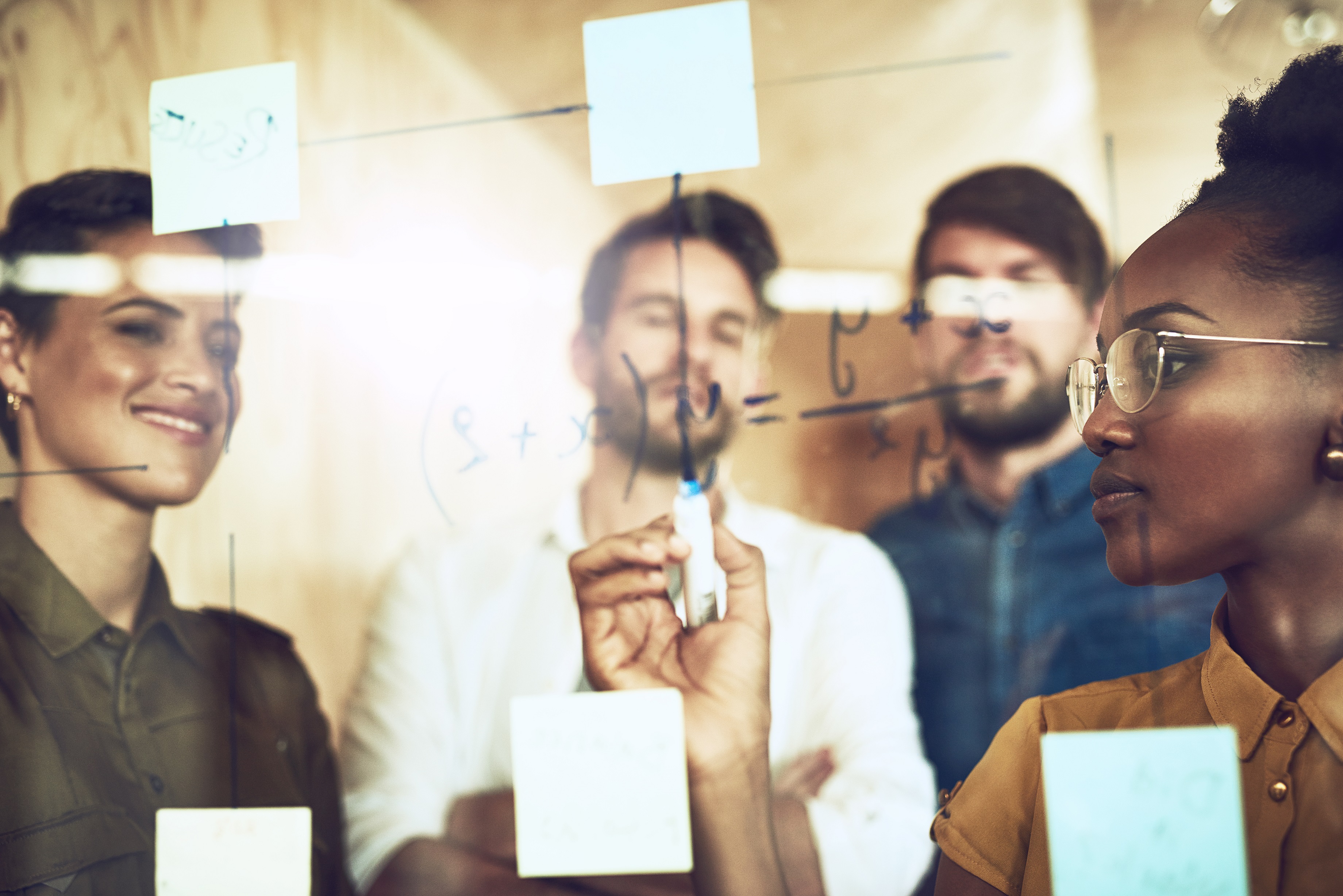Team gathered around clear board with post-it notes