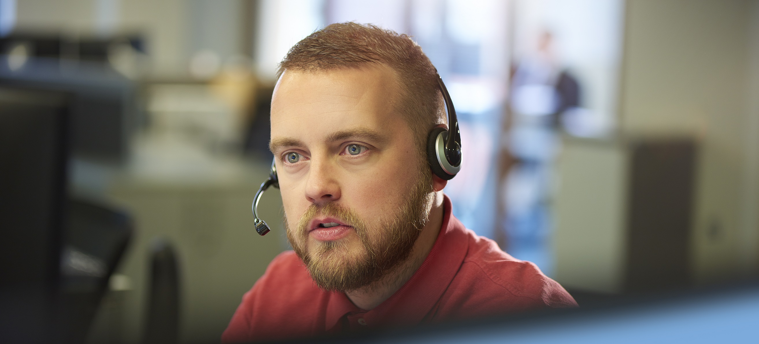 Man using telephone headset in open plan office