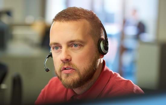 Man using telephone headset in open plan office