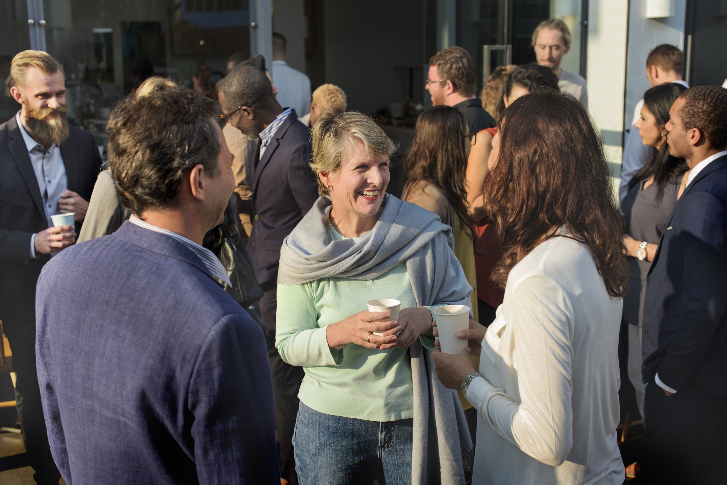 Mixed age and gender professionals networking with drinks outside