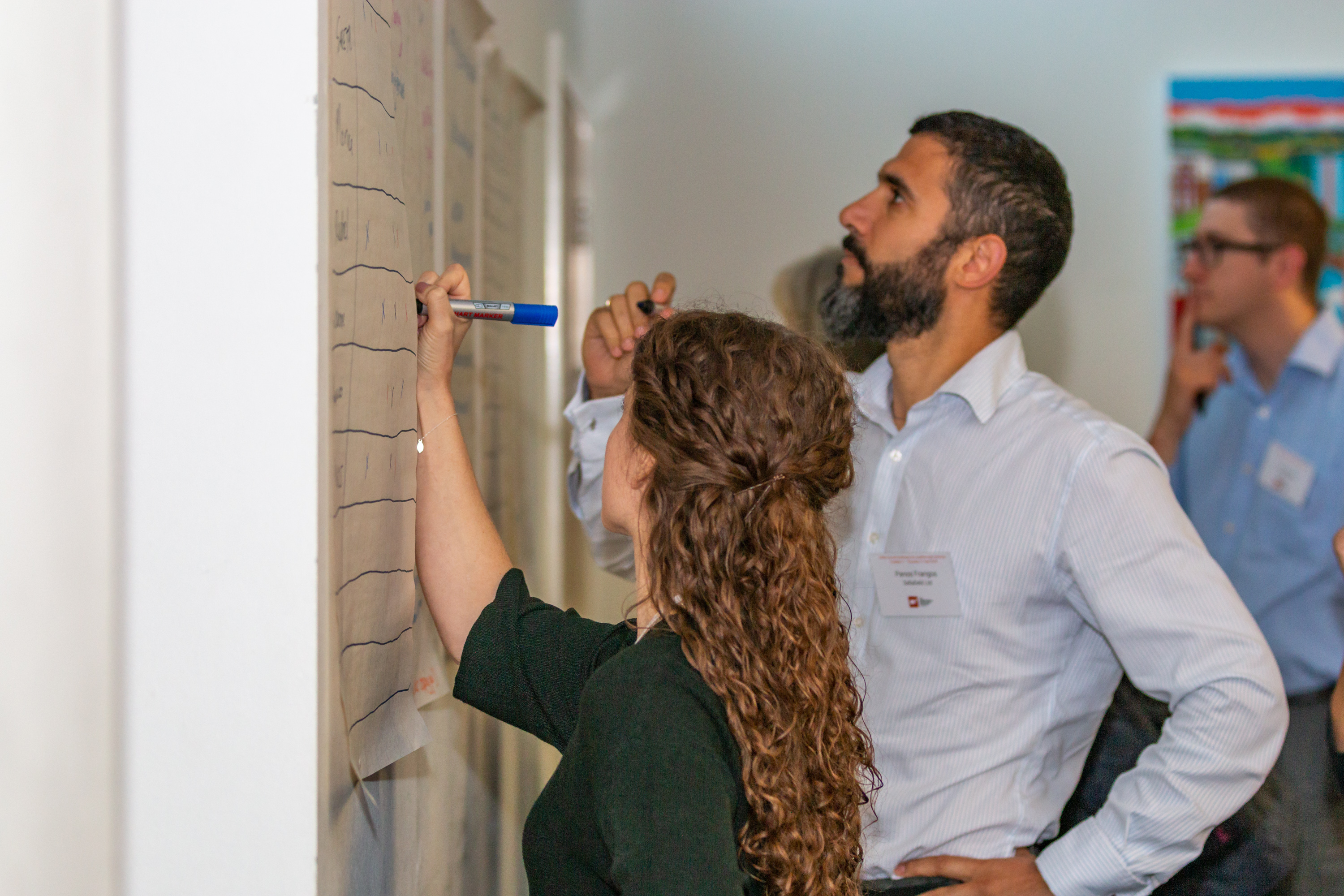 Female and male annual conference delegates write on a wall chart